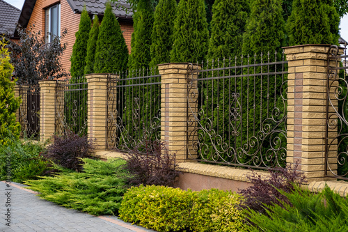 Photography Iron wrought-iron fence between decorative brick columns in front of a residential building