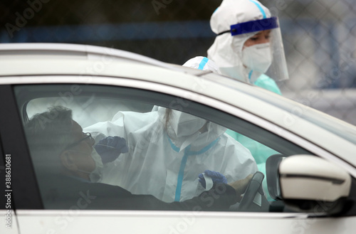 Medical staff member with mask and protective equipment performs Coronavirus nasal swabs test tubes at drive-through testing point in an effort to curb the spread of COVID-19 (novel coronavirus) photo