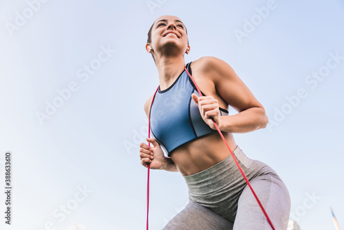 Isolated photo of a young smiling good-looking female sportsman exercising with elastic band photo