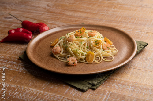 pasta dish with shrimp on wooden table with peppers