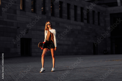Young woman rides a longboard around the city.