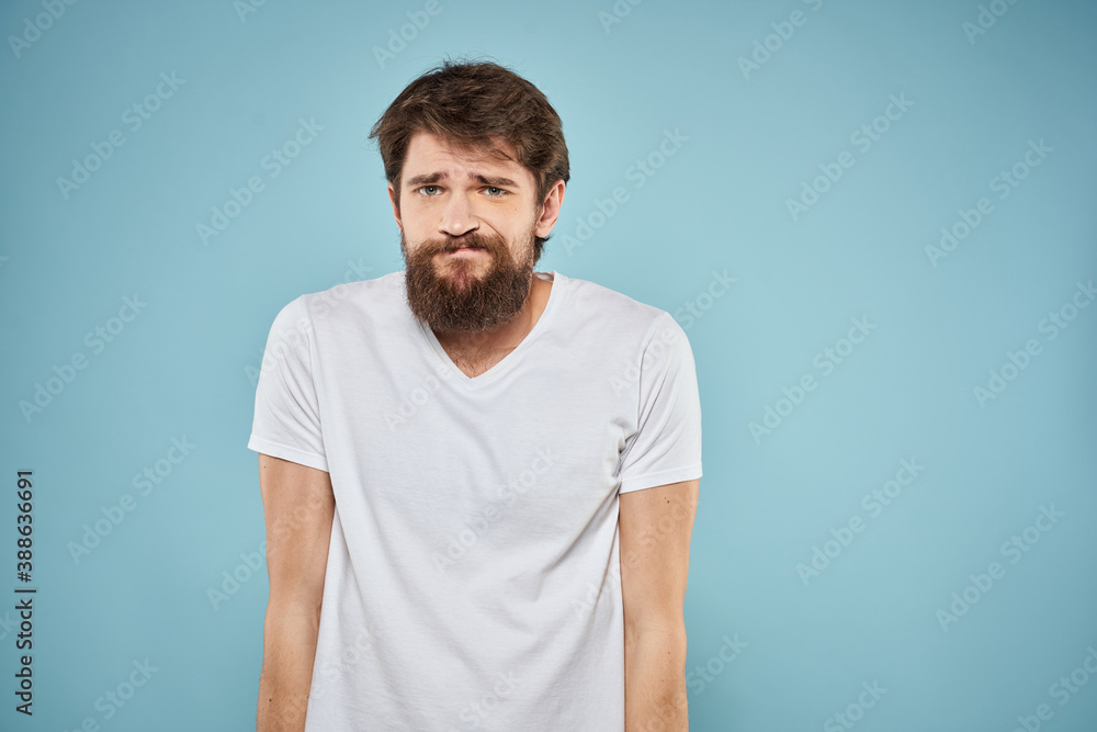 Man in white t-shirt lifestyle studio emotions facial expression blue isolated background Man in white t-shirt lifestyle studio emotions facial expression blue isolated background