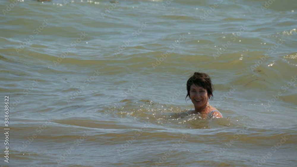 Adult beautiful woman bathes in a dirty sea with seaweed after a storm. Adult beautiful woman bathes in a dirty sea with seaweed after a storm.
