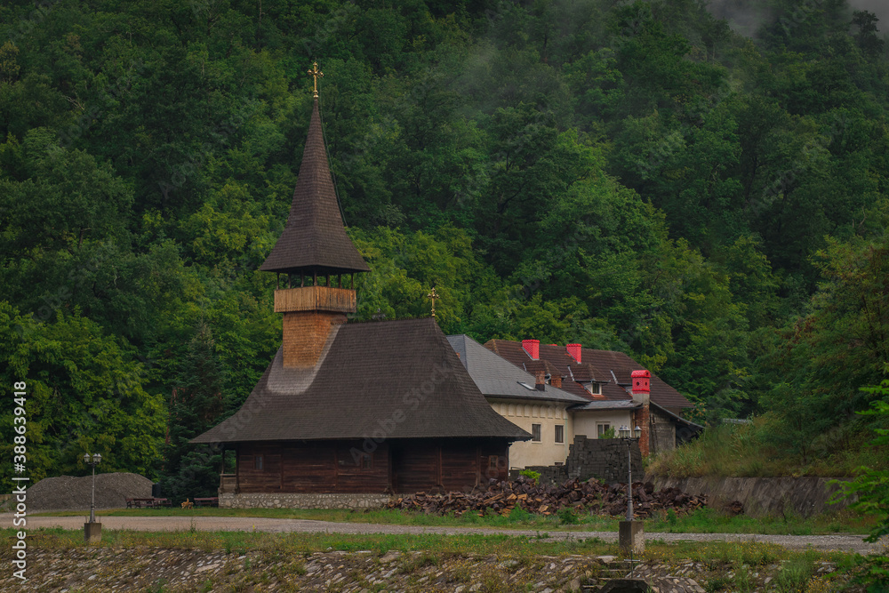View of vodita monastery in Romania on a cloudy dull morning, monastery hiding in thick green forest.