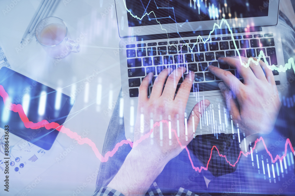 Double exposure of man's hands typing over laptop keyboard and forex chart hologram drawing. Top view. Financial markets concept. Double exposure of man's hands typing over laptop keyboard and forex chart hologram drawing. Top view. Financial markets concept.