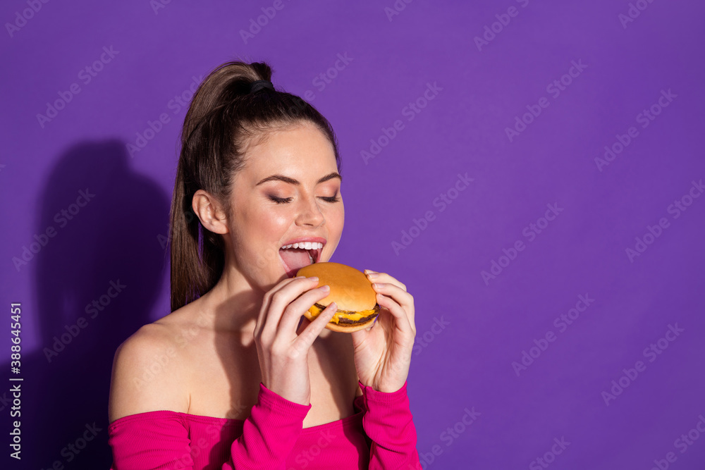 Close-up profile side view portrait of attractive dreamy cheery eating delicious burger copy space isolated on bright violet color background