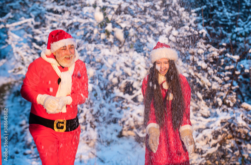 beautiful snowy winter. child and senior man celebrate holiday. winter holiday and vacation. grandpa in santa costume with small girl play snowballs. Santa helper outdoor. winter activity time
