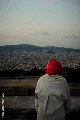 red hooded person in front of a landscape