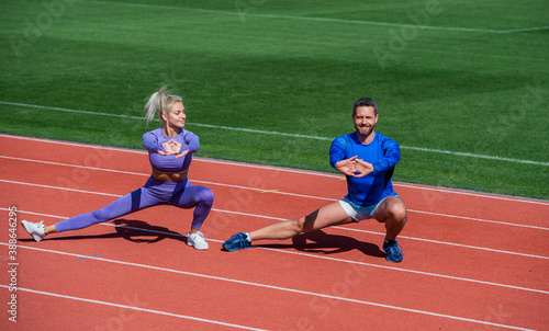 fitness sport couple warming up and stretching together on outdoor stadium racetrack wearing sportswear, workout