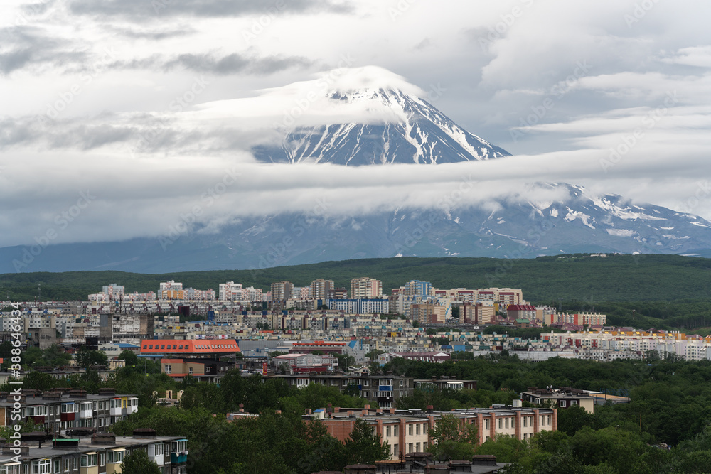 Summer city scape of Kamchatka Peninsula, residential building and urban development of Petropavlovsk-Kamchatsky City on background of active Koryak Volcano. Kamchatka, Russia - July 20, 2019