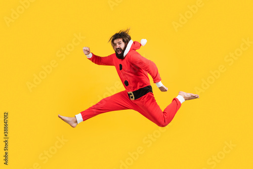 Happy mature guy with Christmas costume jumping against the yellow background, xmas fun