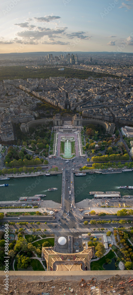 A vertical panoramic view of Paris, France, including the Trocadero Gardens, Homme Museum, Aquarium, and the Seine River, as seen from the top o the Eiffel Tower during a beautiful sunset.