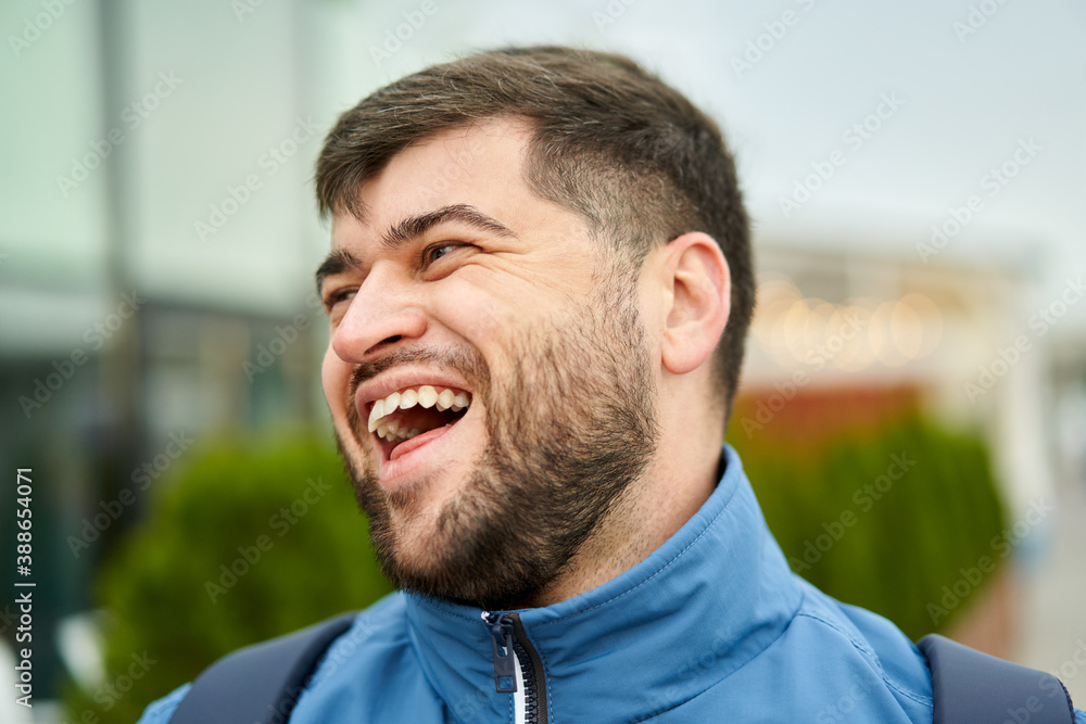 Fototapeta premium Handsome caucasian man with beard walks outdoors and smiles.
