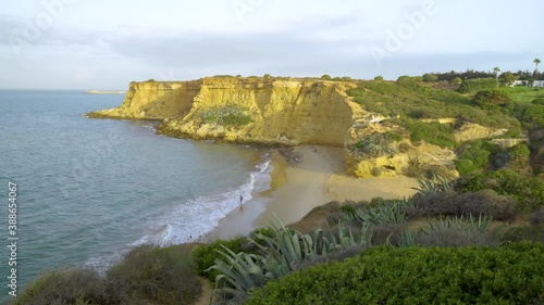 Cala, calita o playa pequeña con forma de herradura, en Conil, Cádiz, Andalucía, España. Aguas del atlántico con oleaje, acantilados dorados por el sol del atardecer y la playa con vegetación. photo