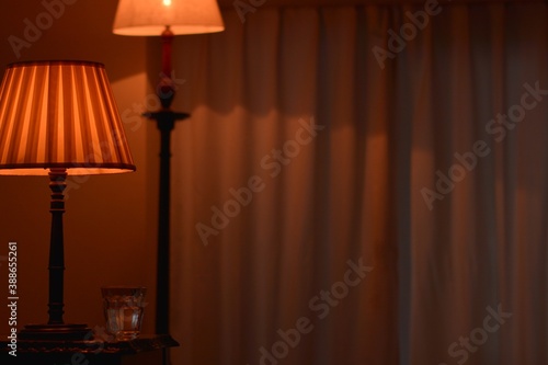 Room of the table shade lamp with stand lamp & mineral water. dim lighting room soft focus image. This expensive antique mahogany furniture is made in England.