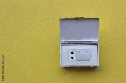 Light switches, light boxes, electrical sockets, 3 electrical outlets on the yellow cement floor beside the wall