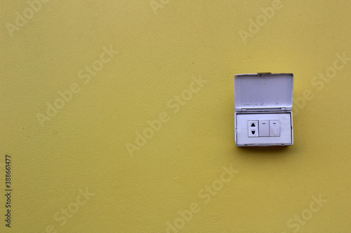 Light switches, light boxes, electrical sockets, 3 electrical outlets on the yellow cement floor beside the wall