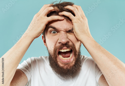 Model bearded man in white T-shirt on blue background irritability emotions model