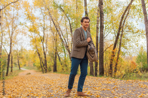 Tall handsome man with a bag on the autumn alley