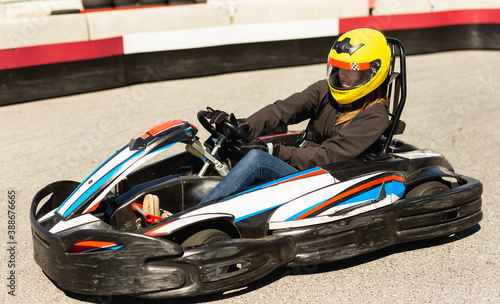 Young woman in helmet driving car for karting in sport club outdoor