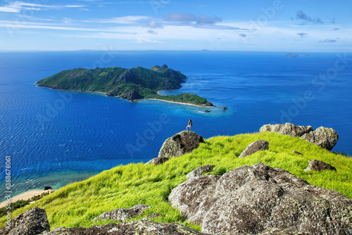 View of Kuata Island from Wayaseva Island with a hiker standing on a rock, Yasawas, Fiji photo