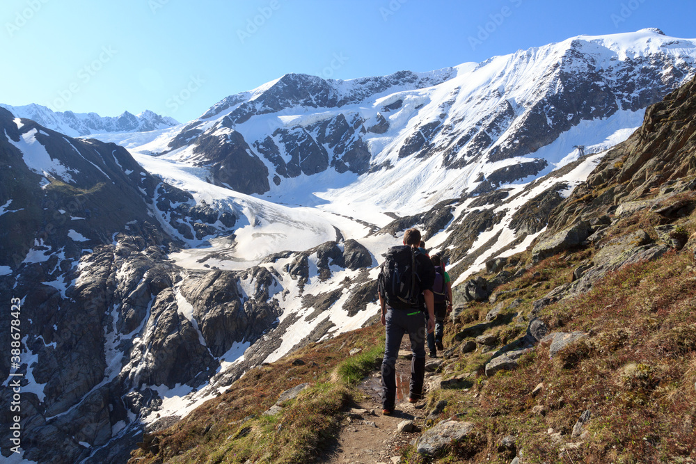 Group of people hiking towards glacier Taschachferner and mountain snow panorama with blue sky in Tyrol Alps, Austria