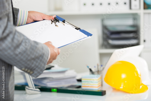 Professional man in jacket near helmet working with documents