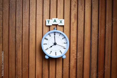 Block letters on tax with alarm clock on wooden table 