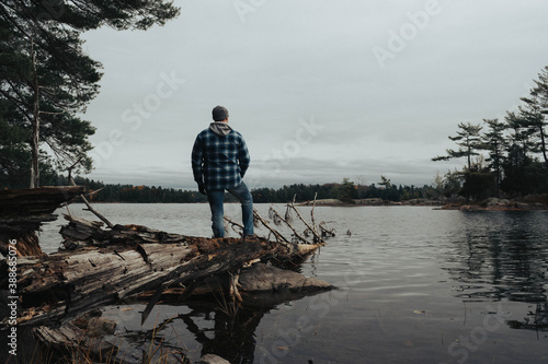 Canadian hiker on a fallen down tree in a lake, surrounded by trees