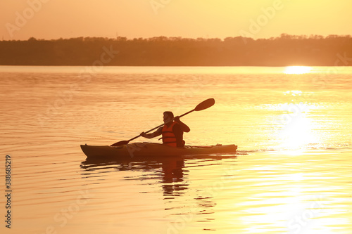 Young man kayaking in river at sunset © Pixel-Shot