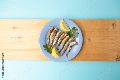 fried sardines, in blue plate with lemon wedge