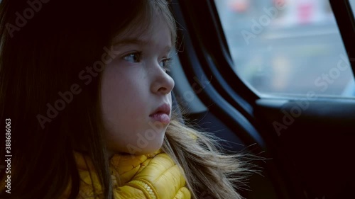 little sad girl rides a car and looks out the window