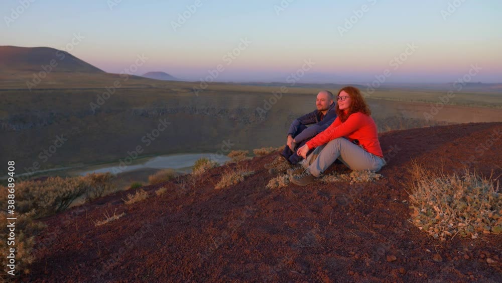 couple of tourists sitting on a volcano near lake Meke in Turkey, watching the sunrise, hiking tourism, mountains at sunrise, Cappadocia, Turkey couple of tourists sitting on a volcano near lake Meke in Turkey, watching the sunrise, hiking tourism, mountains at sunrise, Cappadocia, Turkey