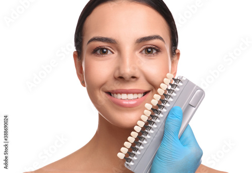 Doctor checking young woman's teeth color on white background. Cosmetic dentistry