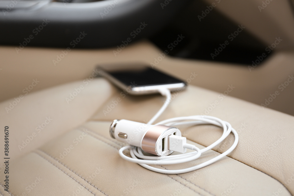 Adapter with connected charging cable and mobile phone in car, closeup Adapter with connected charging cable and mobile phone in car, closeup