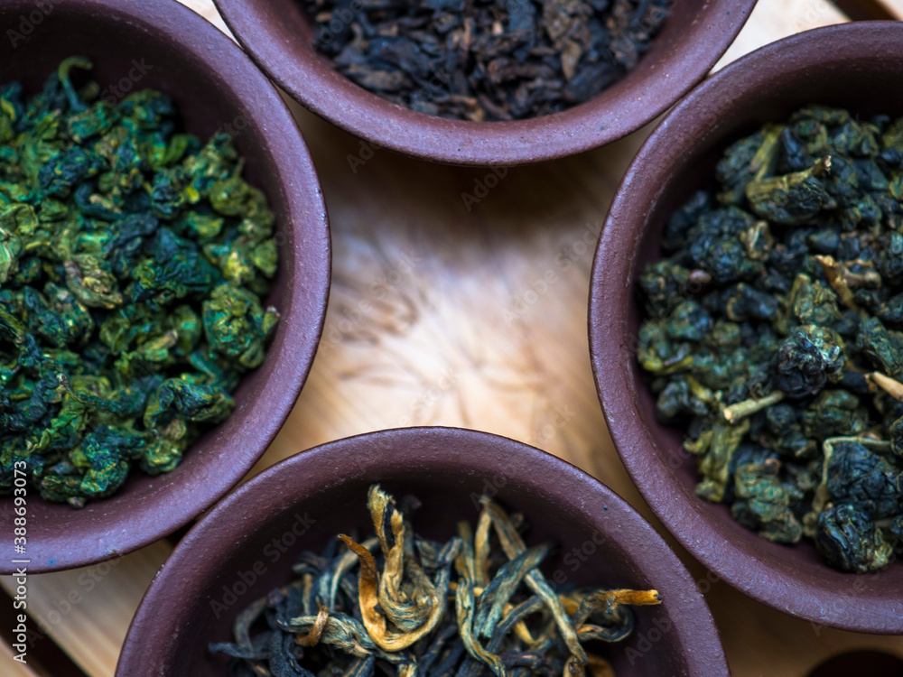 Assortment of Chinese tea in clay bowls on a wooden table Assortment of Chinese tea in clay bowls on a wooden table