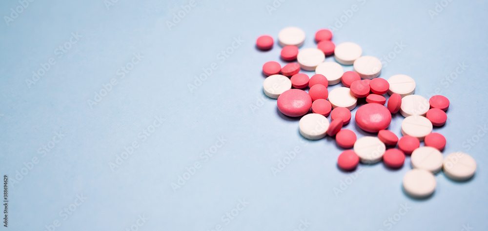 A pile of white and pink pills on blue backgoudn. Medical concept. A pile of white and pink pills on blue backgoudn. Medical concept.