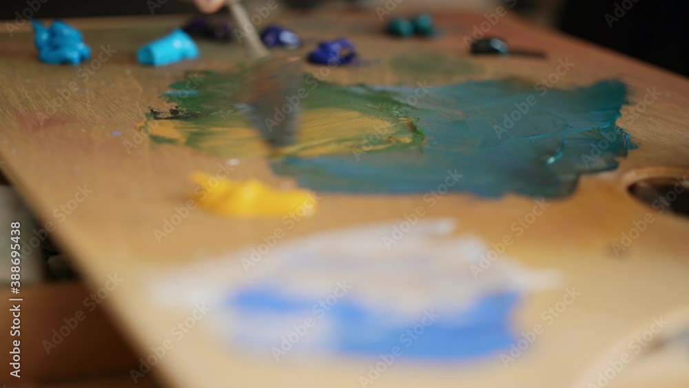 Artist mixes paint on the palette. Art brush and spatula mixed paint on the palette. Close-up. Artist mixes paint on the palette. Art brush and spatula mixed paint on the palette. Close-up.