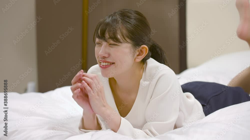 ホテルのベッドの上ではしゃいでいる女性 ホテルのベッドの上ではしゃいでいる女性