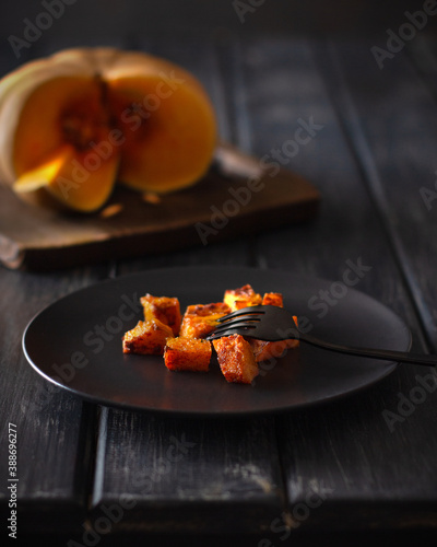 Traditional autumn dish. Baked pumpkin. Roasted pumpkin grilled. Dark mood. Wooden background. copy space. Vertical orientation