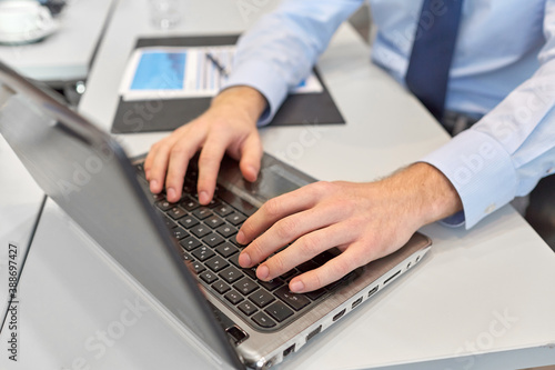 business, people and technology concept - close up of businessman with laptop computer at office