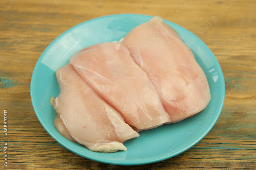 Raw chicken breast fillet in plate on wooden table background. Top View. Raw chicken breast fillet in plate on wooden table background. Top View.