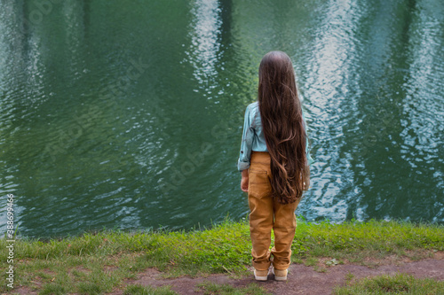 Принти на полотні A girl with long hair stands turned away looks at the river