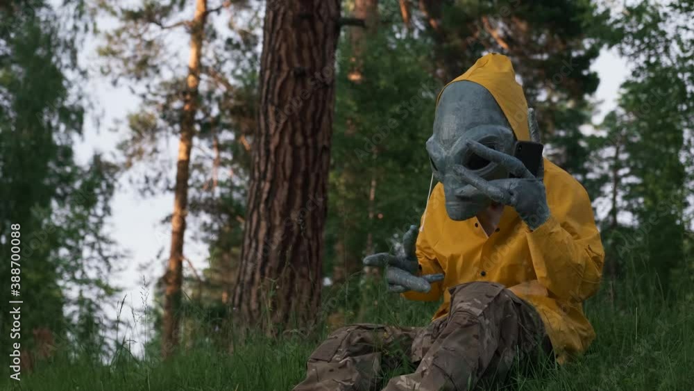 alien in yellow suit in forest talking on the phone, UFO concept, space, alien. alien in yellow suit in forest talking on the phone, UFO concept, space, alien.