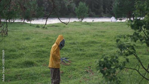 alien in yellow suit in forest near river in nature. goes away looking back, concept of UFO, space, alien.