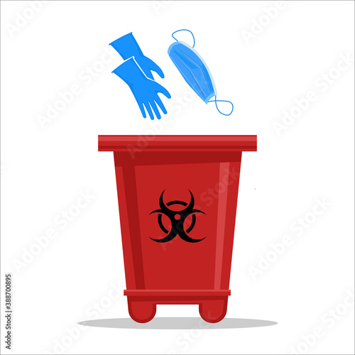Red trash container with the biohazard sign for used latex gloves and surgical masks. Concept of proper disposal of medical waste during the coronavirus pandemic.