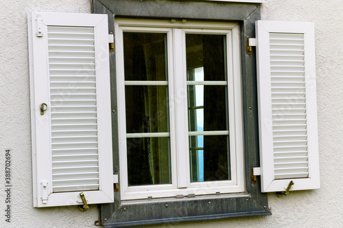 Metal framed window with wood shutters and with white wall