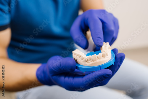 A dentist shows patient ceramic model of teeth and explain to her about work