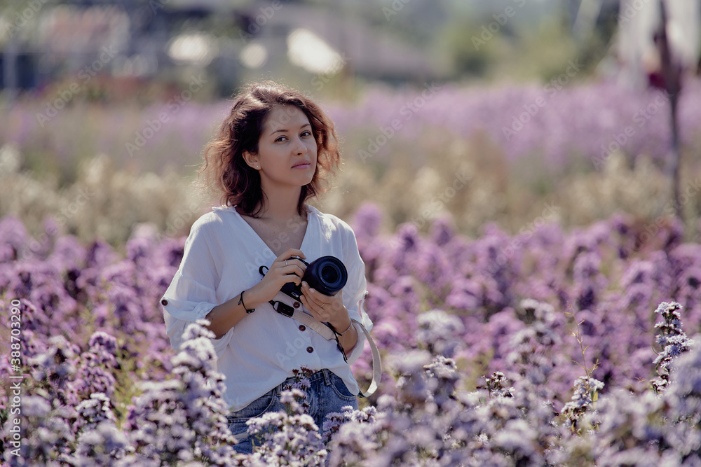 young cute woman professional photographer on a flower field in summer