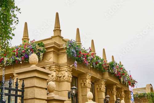 The facade of a one-story old house with a decorative fence is decorated with stucco and flowers